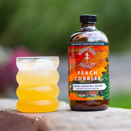 Bottle of Peach Cobbler syrup on a stone surface with a blurred garden background